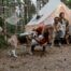 A group of friends camping with a dog - beagle shown with smiling group in front of a campsite.